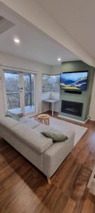 a living room with a large couch and a tv at Treetop Leura Deluxe Family Cabin in Leura