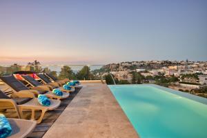 a row of lounge chairs next to a swimming pool at Maltese Luxury Villas - Sunset Infinity Pools, Indoor Heated Pools and More! in Mellieħa