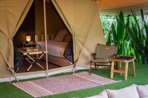 une tente avec un lit, un bureau et une chaise dans l'établissement CAMP CAYLA - EDEN, à Chiang Mai