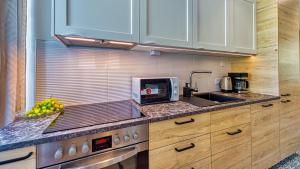 a kitchen with wooden cabinets and a sink and a microwave at Apartament Górska 5 by Royal Aparts in Świeradów-Zdrój