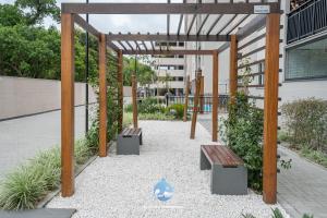 a pergola with two benches in front of a building at Aptos em Bal Piçarras a150m da PRAIA, dois quartos, sala de estar, COZINHA COMPLETA, SACADA com CHURRASQUEIRA, WI-FI, PISCINA, PORTARIA 24h, PLAYGROUND e QUADRA DE ESPORTES in Piçarras