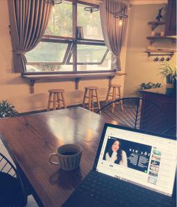 a laptop sitting on a table with a cup of coffee at BabaHouse-Homestay Thành phố Vinh in Bến Thủy