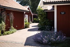 una pasarela entre dos edificios rojos con flores púrpuras en Gränsö Slott Hotel & Spa en Västervik