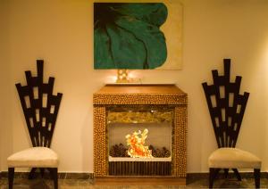 una chimenea con chimenea y 2 sillas en Blueberry Hotel zirakpur-A Family hotel with spacious and hygenic rooms, en Chandīgarh