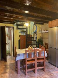 y cocina con mesa, sillas y nevera. en La herradura, acogedora casa en Montemayor del Río, en Montemayor del Río