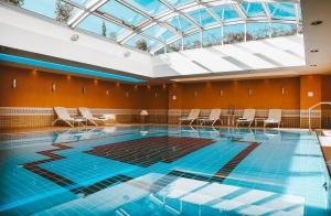 a swimming pool with a skylight and chairs in a building at Hilton Imperial Dubrovnik in Dubrovnik