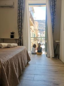 2 bambini seduti sul pavimento in una camera da letto con finestra di Ovidio home a Palermo