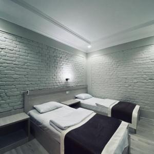 1 dormitorio con 2 camas y pared de ladrillo en ZARINA SAMARKAND, en Samarkand