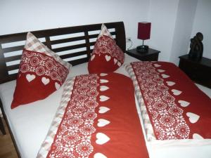 a bed with red and white pillows on it at Meister-s-Ferienhaus-Tiere-herzlich-willkommen-Koenigswinkel in Karlsebene