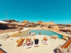 a pool at a resort with people sitting in chairs at New Moon Island Camp in Nuweiba