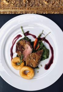 un plato blanco de comida con carne y verduras en Hotel Alpenland, en Moso in Passiria