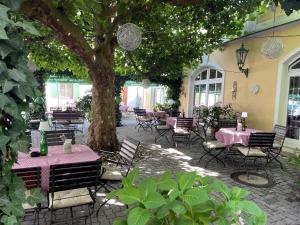 a patio with tables and chairs under a tree at Hotel Jungbräu in Abensberg