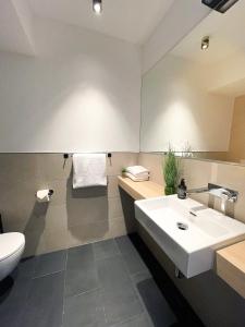 La salle de bains est pourvue d'un lavabo blanc et de toilettes. dans l'établissement HOLI City Apart Hotel Berlin, à Berlin