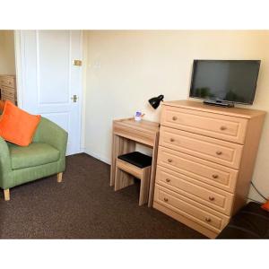 a room with a dresser with a television and a chair at Scardroy Falkirk - 3 Bedroom Apartment in Falkirk