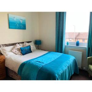 a bedroom with a bed with blue sheets and a window at Scardroy Falkirk - 3 Bedroom Apartment in Falkirk