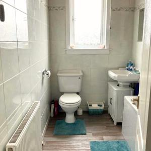 a bathroom with a toilet and a sink and a window at Scardroy Falkirk - 3 Bedroom Apartment in Falkirk