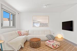 MEDANO4YOU The Bahia Beach Shack في إل ميدانو: غرفة معيشة بيضاء مع أريكة وتلفزيون