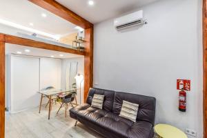 loft reformado en chueca para 4 personas في مدريد: غرفة معيشة مع أريكة جلدية وطاولة