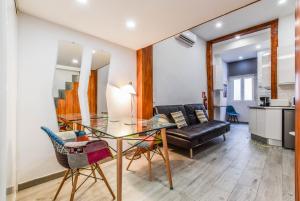 comedor y sala de estar con mesa de cristal y sillas en loft reformado en chueca para 4 personas en Madrid