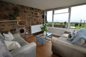 uma sala de estar com dois sofás e uma parede de pedra em Clover Cottage countryside retreat with sea views em Crail