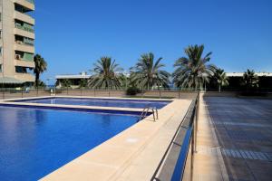a swimming pool with palm trees and a building at Apartamento dos habitaciones primera línea de playa in Valencia