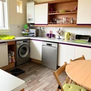 a kitchen with a washing machine and a table at Scardroy Falkirk - 3 Bedroom Apartment in Falkirk