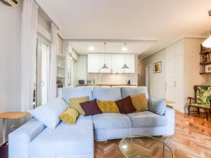 una sala de estar con un sofá blanco con almohadas en apartamento reformado-2 habitaciones-5 huespedes, en Madrid