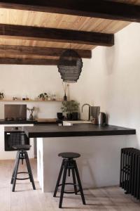 une cuisine avec un comptoir noir et deux tabourets dans l'établissement VESTIGES, ancien corps de ferme rénové selon l'esprit wabi-sabi, à Saint-Antonin