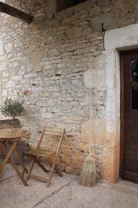 een houten tafel en stoel naast een stenen muur bij VESTIGES, ancien corps de ferme rénové selon l'esprit wabi-sabi in Saint-Antonin