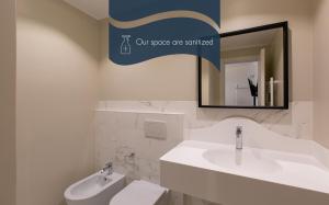 bagno con lavandino, servizi igienici e specchio di Daplace - Corso Monforte Suites a Milano