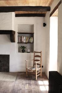 une chaise assise dans une pièce avec cheminée dans l'établissement VESTIGES, ancien corps de ferme rénové selon l'esprit wabi-sabi, à Saint-Antonin