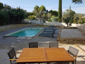a wooden table and chairs next to a swimming pool at Maison avec piscine in Vaison-la-Romaine