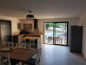 a kitchen and dining room with a table and a view of a pool at Maison avec piscine in Vaison-la-Romaine