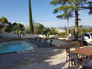 patio ze stołem i krzesłami oraz basenem w obiekcie Maison avec piscine w mieście Vaison-la-Romaine