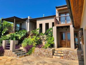a house with a stone wall and a wooden door at Bushmans River Lodge in Kenton on Sea