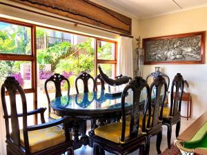 a dining room with a table and chairs and windows at Bushmans River Lodge in Kenton on Sea