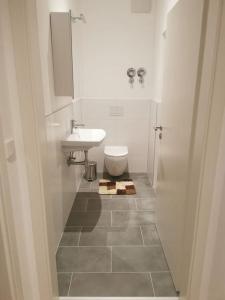 ein weißes Bad mit einem Waschbecken und einem WC in der Unterkunft Apartment in Natrup-Hagen 