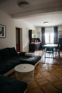 Macao Apartmani في فينكوفسي: غرفة معيشة مع أريكة سوداء وطاولة