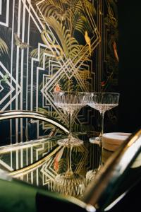 due bicchieri da vino seduti su un tavolo di fronte a un muro di Rooms of Renown - The Gilded Globe a Leeton