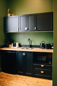 a kitchen with black cabinets and a sink and a microwave at Rooms of Renown - The Gilded Globe in Leeton
