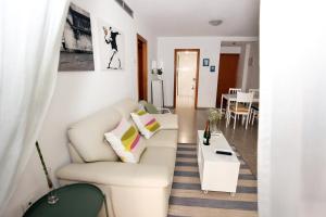 een woonkamer met een witte bank en een tafel bij Apartamento dos habitaciones primera línea de playa in Valencia