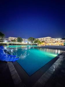 ein großer Swimmingpool in der Nacht mit Gebäuden im Hintergrund in der Unterkunft Eraora Hotel Village in Battipaglia
