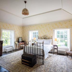 a bedroom with a bed and a desk and windows at Tullymurry House in Newry