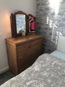 a bedroom with a dresser with a mirror and a bed at Pats house in Earlswood