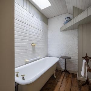 uma banheira na casa de banho com paredes de tijolos brancos em Merrion Mews em Dublin