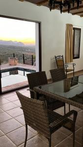 eine Terrasse mit einem Glastisch und Stühlen sowie einem Balkon in der Unterkunft Cortijo Borreguero in Villanueva del Trabuco