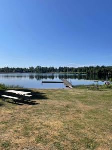 a picnic table and a dock on a lake at Skeens Nygård in Skeen