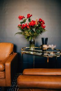 uma mesa de vidro com um vaso de flores vermelhas em Rooms of Renown - The Panaretto Parlour em Leeton