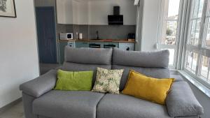 a gray couch with colorful pillows in a living room at Lar ABEANCOS in Melide