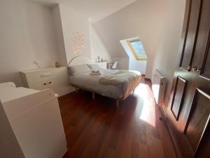 een kleine slaapkamer met een bed en een houten vloer bij Increible Ático centro Monachil in Monachil